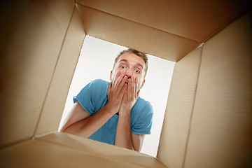 Image showing Man smiling, unpacking and opening carton box and looking inside