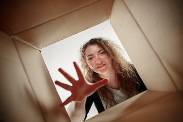 Image showing Woman unpacking and opening carton box and looking inside