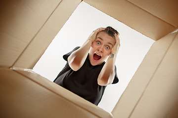 Image showing Woman unpacking and opening carton box and looking inside