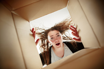 Image showing Woman unpacking and opening carton box and looking inside