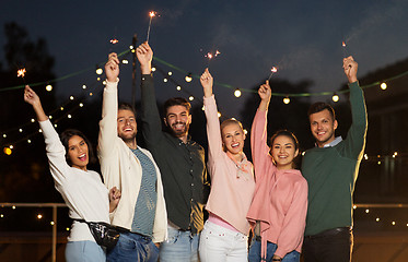 Image showing happy friends with sparklers at rooftop party