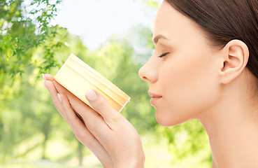 Image showing beautiful woman smelling moisturizing cream aroma