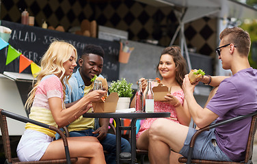 Image showing happy friends with drinks eating at food truck