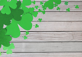 Image showing green paper shamrocks on wooden background