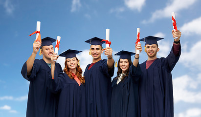 Image showing graduates in mortar boards with diplomas