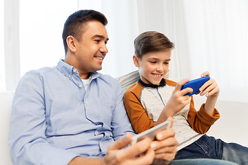 Image showing happy father and son with smartphones at home