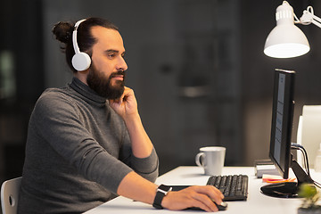 Image showing creative man in headphones working at night office