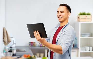 Image showing happy young man with tablet computer in kitchen