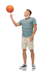 Image showing smiling young man spinning ball on finger