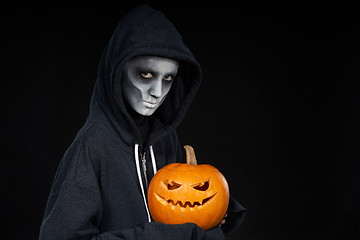 Image showing Boy with Halloween makeup holding Jack O\'Lantern pumpkin on black background