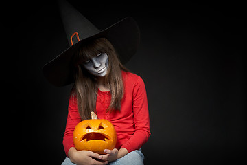 Image showing Serious Halloween witch holding Jack O\'Lantern pumpkin looking at camera