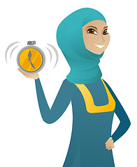 Image showing Young muslim business woman holding alarm clock.