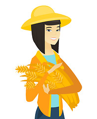 Image showing Young asian farmer holding hay in hands.