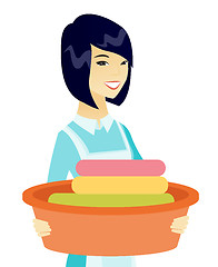 Image showing Asian housewife holding basin with dirty linen.