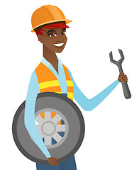 Image showing Young african mechanic with tyre and spanner.