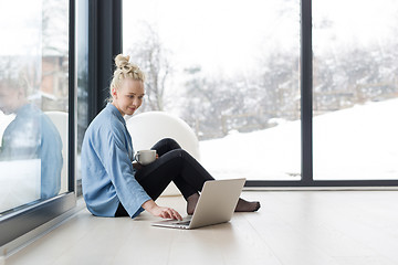 Image showing woman drinking coffee and using laptop at home
