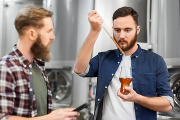 Image showing men with pipette testing craft beer at brewery