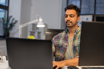 Image showing creative man with laptop working at night office