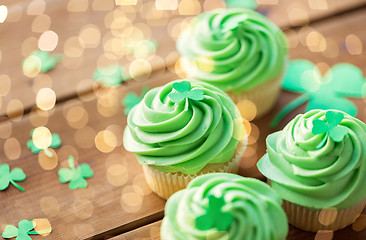 Image showing green cupcakes and shamrock on wooden table