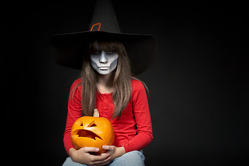 Image showing Serious Halloween witch holding Jack O\'Lantern pumpkin looking at camera