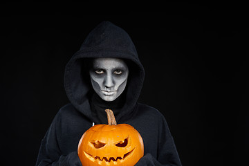 Image showing Boy with Halloween makeup holding Jack O\'Lantern pumpkin on black background