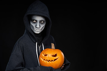 Image showing Boy with Halloween makeup holding Jack O\'Lantern pumpkin on black background