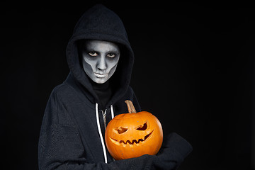 Image showing Boy with Halloween makeup holding Jack O\'Lantern pumpkin on black background