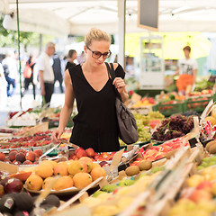 Image showing Woman buying fruits and vegetables at local food market. Market stall with variety of organic vegetable