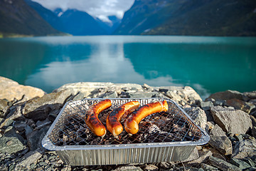 Image showing Grilling sausages on disposable barbecue grid.