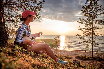 Image showing Woman at sunset playing the ukulele