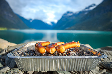 Image showing Grilling sausages on disposable barbecue grid.