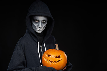 Image showing Boy with Halloween makeup holding Jack O\'Lantern pumpkin on black background