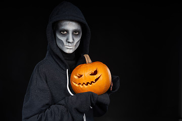 Image showing Boy with Halloween makeup holding Jack O\'Lantern pumpkin on black background