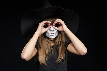 Image showing Closeup of Halloween witch girl looking at camera through fingers making binoculars