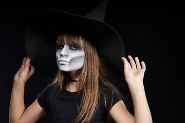 Image showing Closeup of Halloween witch girl looking at camera on black background.