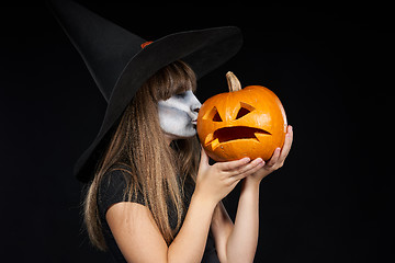 Image showing Halloween witch girl giving a kiss to Jack-O-Lantern pumpkin