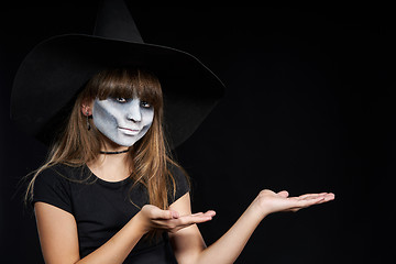 Image showing Halloween witch girl looking at camera showing blank copy space on her palms