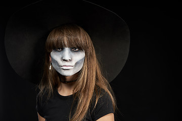 Image showing Serious Halloween witch holding Jack-O-Lantern pumpkin looking at camera