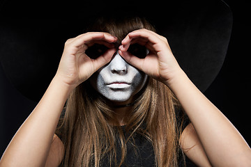 Image showing Closeup of Halloween witch girl looking at camera through fingers making binoculars