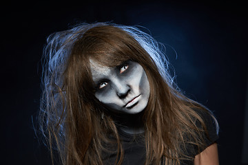 Image showing A girl with zombie makeup over dark background with smoke and backlight