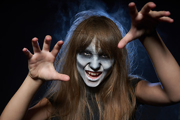 Image showing A girl with zombie makeup over dark background with smoke and backlight