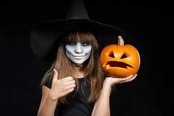 Image showing Halloween witch girl showing Jack-O-Lantern pumpkin on palm