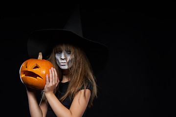 Image showing Serious Halloween witch holding Jack-O-Lantern pumpkin looking at camera