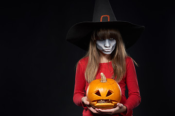 Image showing Serious Halloween witch holding Jack O\'Lantern pumpkin looking a