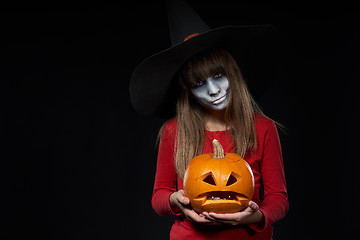 Image showing Serious Halloween witch holding Jack O\'Lantern pumpkin looking at camera