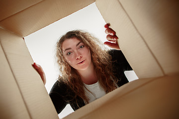 Image showing Woman unpacking and opening carton box and looking inside