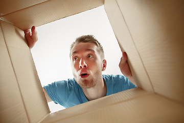 Image showing Man smiling, unpacking and opening carton box and looking inside