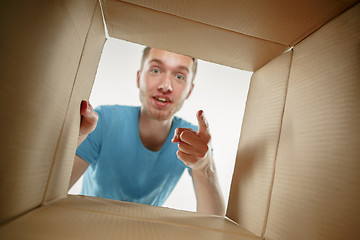 Image showing Man smiling, unpacking and opening carton box and looking inside