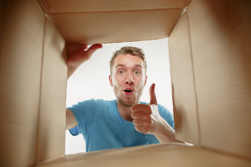 Image showing Man smiling, unpacking and opening carton box and looking inside