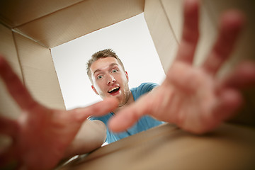 Image showing Man smiling, unpacking and opening carton box and looking inside